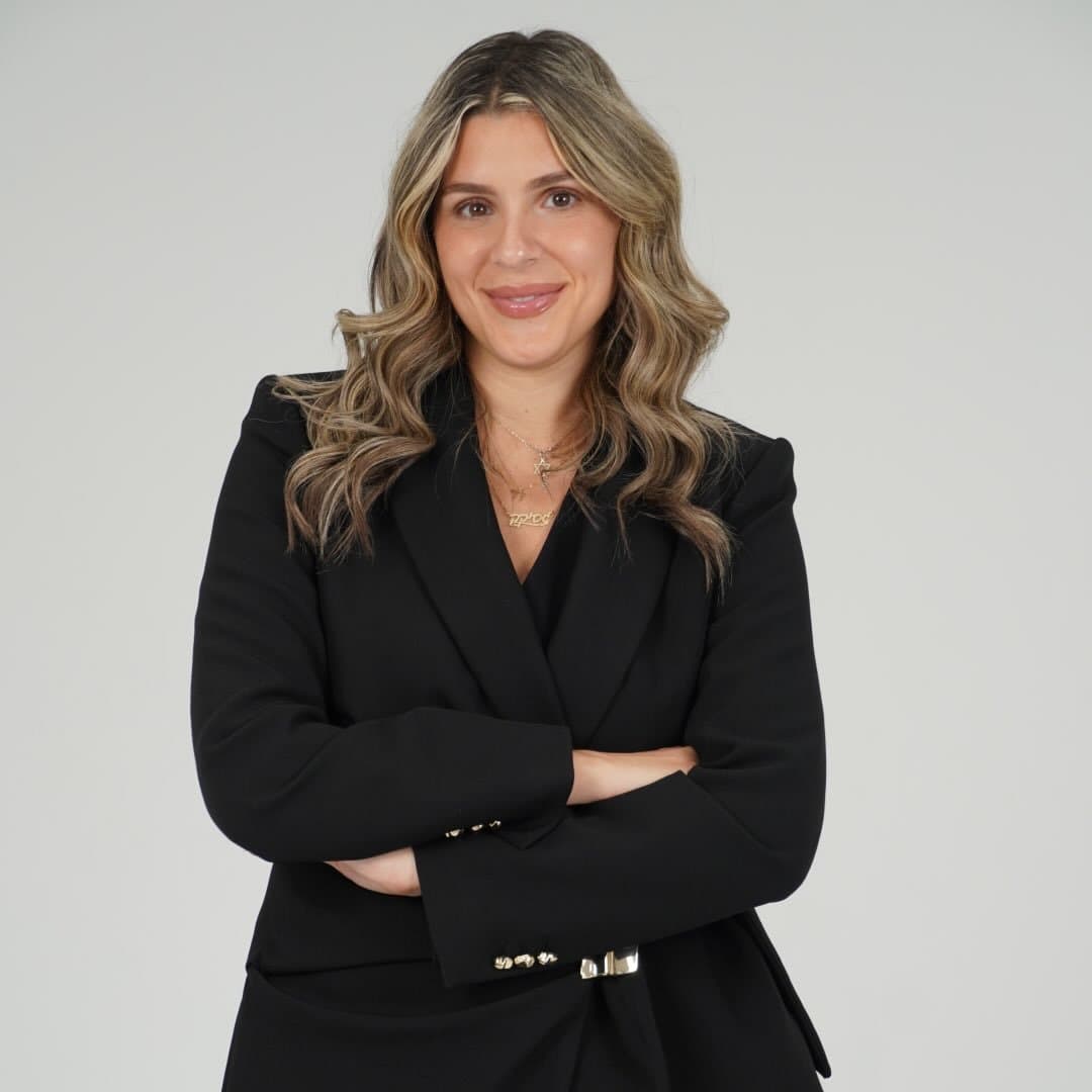 Jessica Sonino, Realtor®, in a black blazer with her arms crossed against a light studio backdrop
