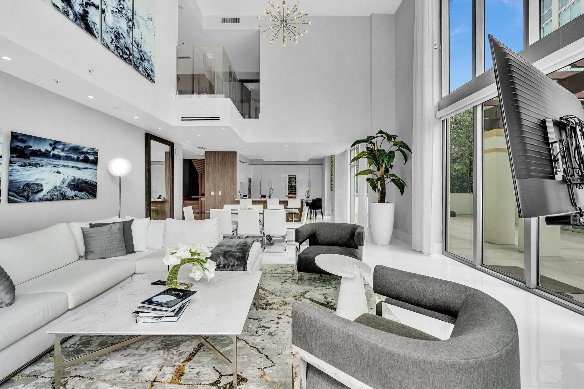 Double-height great room at Parque Towers residence 4-502 in Sunny Isles Beach, with a sputnik chandelier and floor-to-ceiling windows